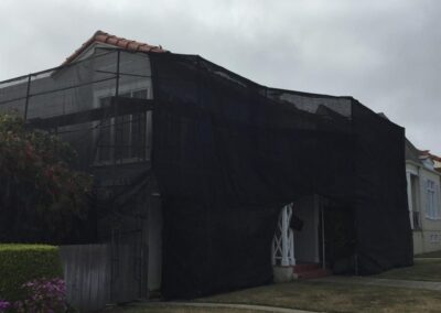 A house covered by a black tarp.